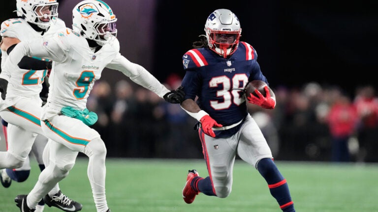 New England Patriots running back Rhamondre Stevenson, right, runs against Miami Dolphins safety Ifeatu Melifonwu during the second half of an NFL football game in Foxborough, Mass., Sunday, Jan. 4, 2026.