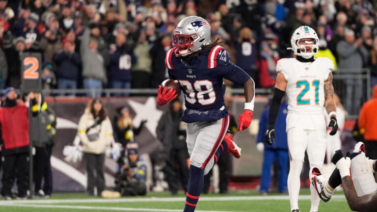New England Patriots running back Rhamondre Stevenson, left, score a touchdown past Miami Dolphins safety Ashtyn Davis during the first half of an NFL football game in Foxborough, Mass., Sunday, Jan. 4, 2026.