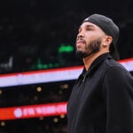 Boston Celtics forward Jayson Tatum, who is out with an injury, stands near the bench during a time out in the first half of an NBA basketball game against the Denver Nuggets, Wednesday, Jan. 7, 2026, in Boston.