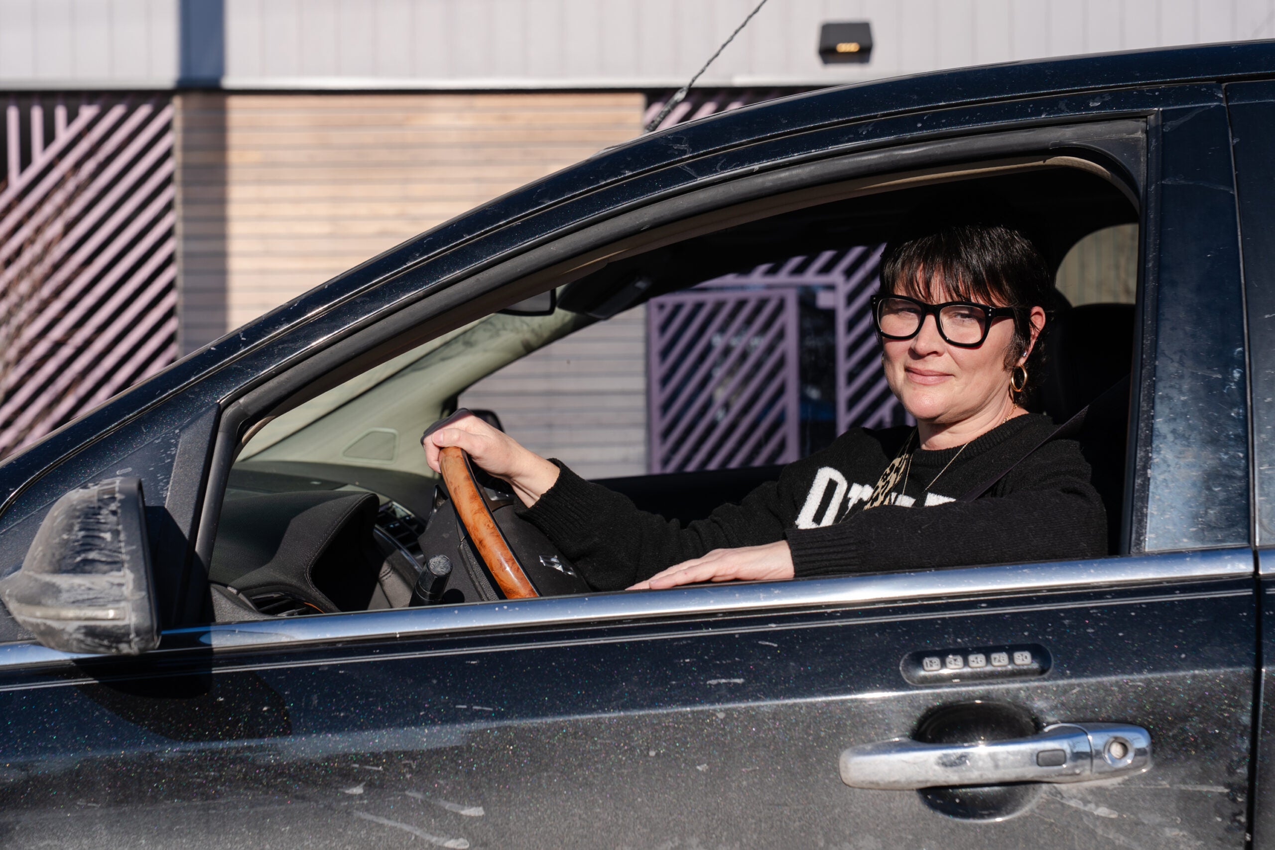 Shandy Priddy sits in the driver's seat of a car. 