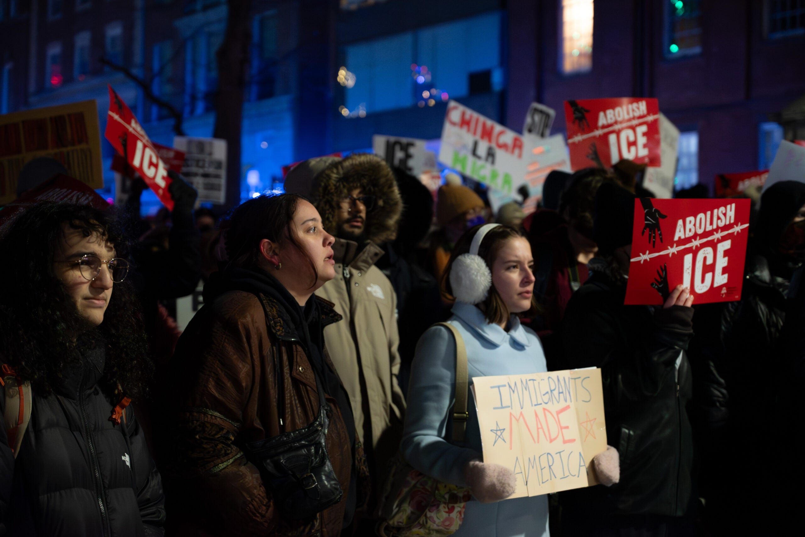 Attendees listen and hold signs as the rally concludes.