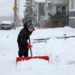 A 5-year-old helps his dad shovel the walkway in front of his house in Quincy, Mass.