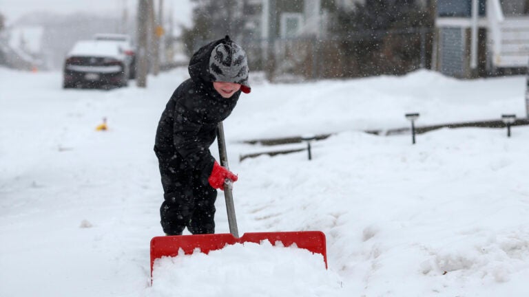A 5-year-old helps his dad shovel the walkway in front of his house in Quincy, Mass.