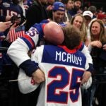 Gold medalist Charlie McAvoy #25 of Team United States celebrates with a fan following the Men's Gold Medal match between Canada and the United States on day 16 of the Milano Cortina 2026 Winter Olympic games at Milano Santagiulia Ice Hockey Arena on February 22, 2026 in Milan, Italy.