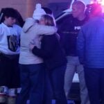 Women embrace Monday at the scene of a mass shooting at an ice rink in Pawtucket.