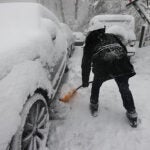 A man digs out his cars from the snow.