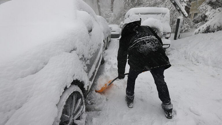 A man digs out his cars from the snow.