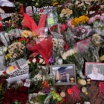 Photos of Brown University shooting victims Mukhammad Aziz Umurzokov and Ella Cook are seen amongst flowers at a makeshift memorial.