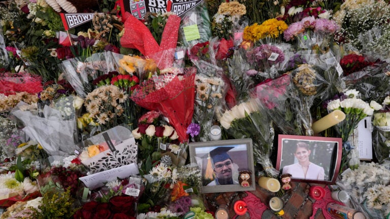 Photos of Brown University shooting victims Mukhammad Aziz Umurzokov and Ella Cook are seen amongst flowers at a makeshift memorial.