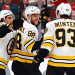 Boston Bruins right wing David Pastrnak (88) reacts with teammates Marat Khusnutdinov and Fraser Minten after scoring during the first period of an NHL hockey game against the New Jersey Devils, Monday, March 16, 2026, in Newark, N.J.