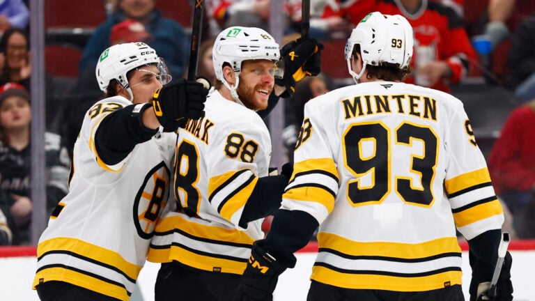Boston Bruins right wing David Pastrnak (88) reacts with teammates Marat Khusnutdinov and Fraser Minten after scoring during the first period of an NHL hockey game against the New Jersey Devils, Monday, March 16, 2026, in Newark, N.J.