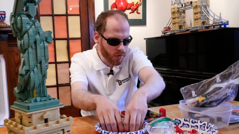 Matthew Shifrin, the founder of Bricks for the Blind, feels for specific pieces while building a LEGO gumball machine.