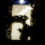 A pedestrian checks his phone as he takes cover under an umbrella as rain falls in Boston.