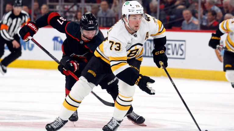Boston Bruins' Charlie McAvoy (73) moves the puck away from Carolina Hurricanes' Andrei Svechnikov (37) during the first period of an NHL hockey game in Raleigh, N.C., Tuesday, April 7, 2026.