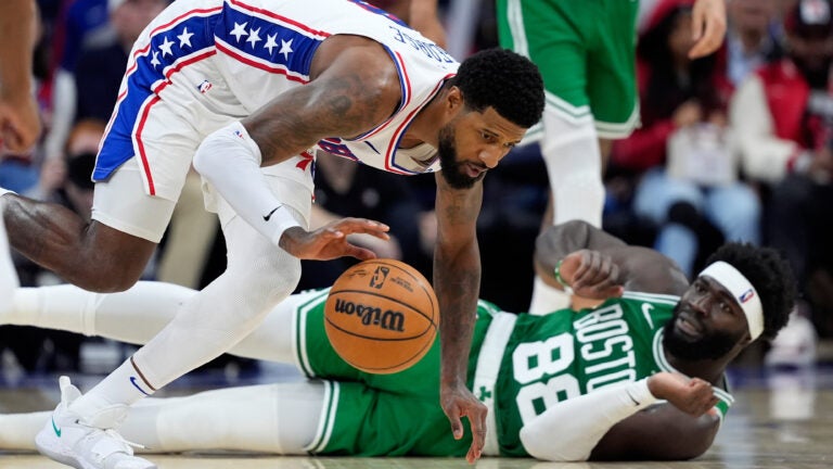 Philadelphia 76ers' Paul George, left, chases a loose ball past the Boston Celtics' Neemias Queta