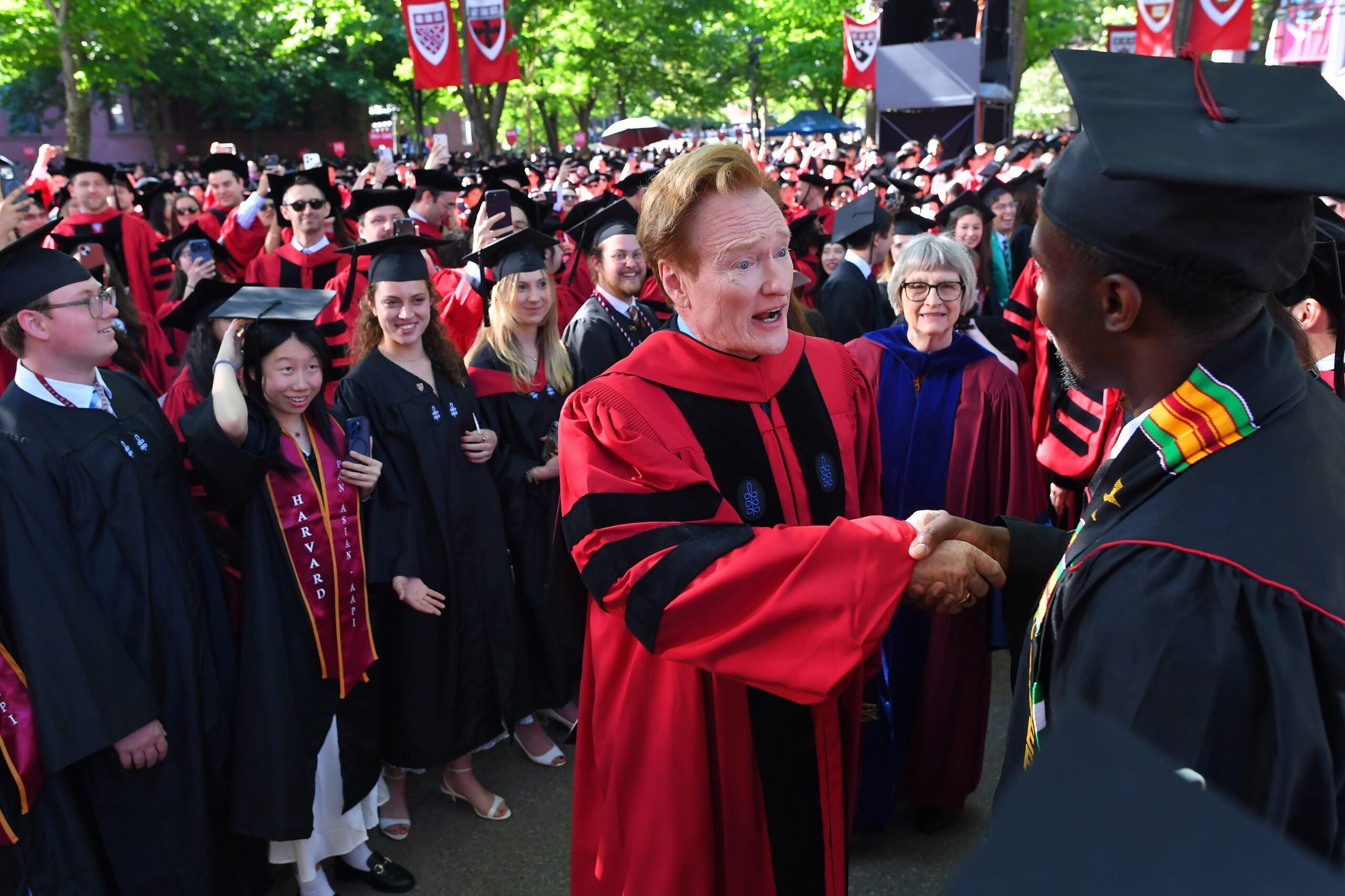Comedian Conan O'Brien greets people while walking in a procession through Harvard Yard, before delivering a commencement address during Harvard University commencement exercises on the school's campus, Thursday, May 28, 2026, in Cambridge, Mass.