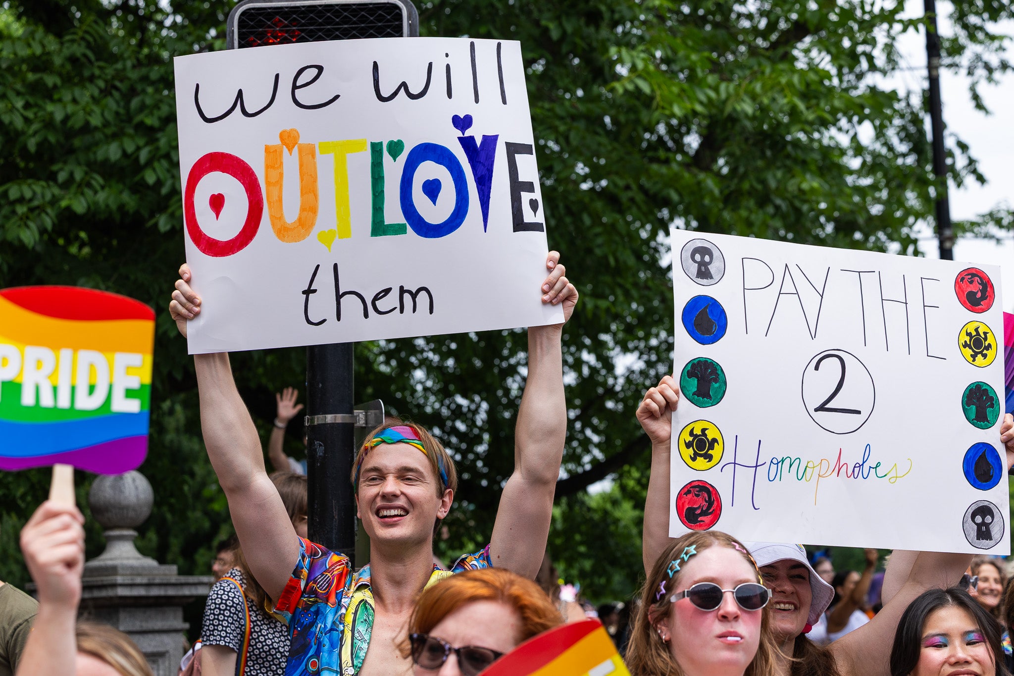 Attendees at the Boston Pride for the People festivities hold up celebratory signs.