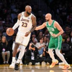 Los Angeles Lakers forward LeBron James dribbles as Boston Celtics guard Derrick White plays defense during the first half of an NBA basketball game, Sunday, Feb. 22, 2026, in Los Angeles.