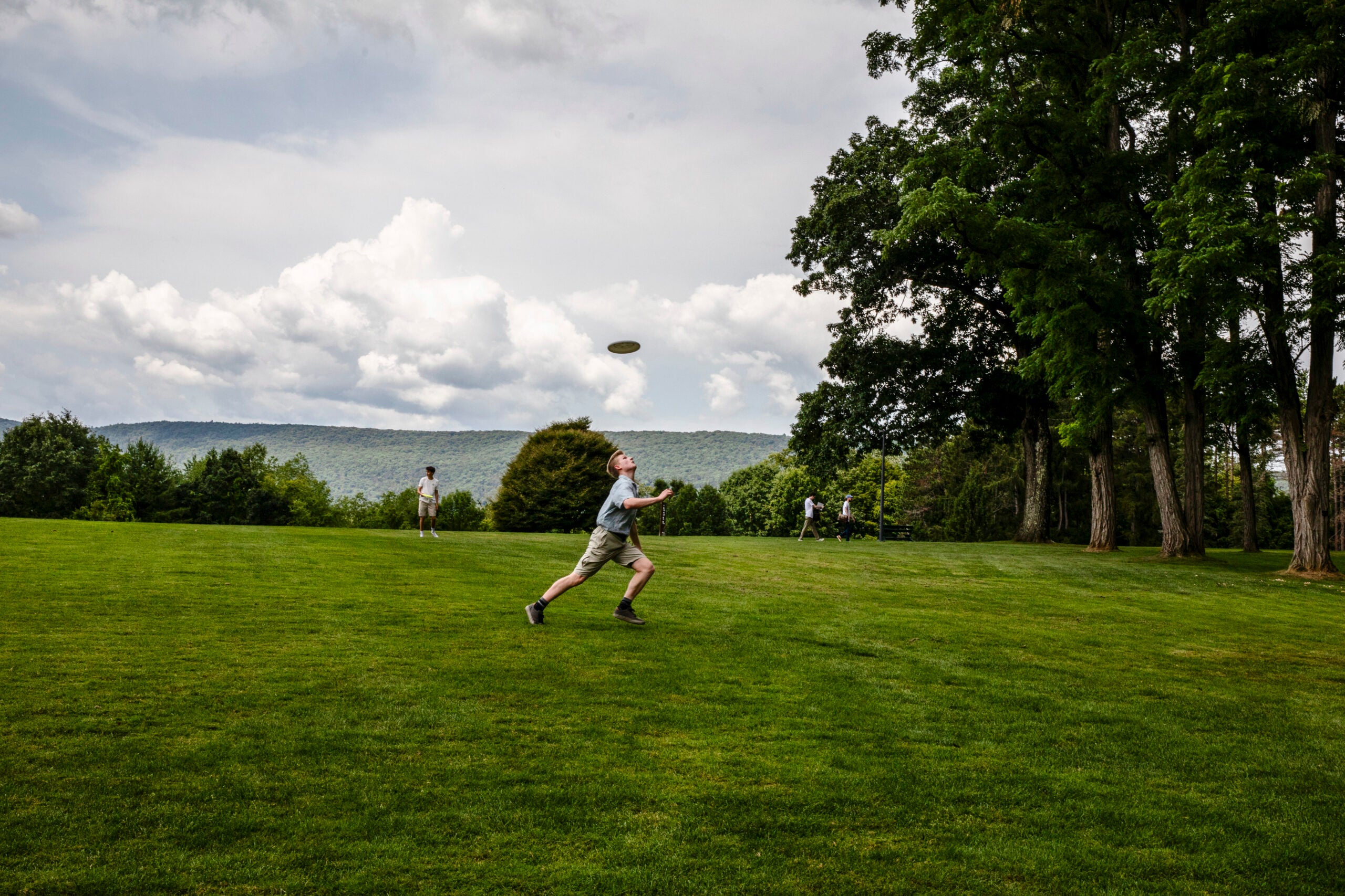 Attendees play frisbee on grass.