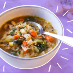 A bowl of soup on a table with a purple background