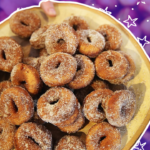 A plate of apple cider doughnuts against a purple background with star graphics