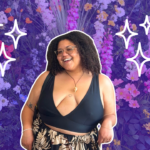 A woman in a black sleeveless plunging top poses and smiles in front of a flower wall. The flower wall background is faded to purple, and there are white sketch sparkles around the sides of her head.