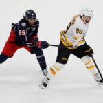 Boston Bruins' David Pastrnak, right, carries the puck into the offfensive zone as Columbus Blue Jackets' Kirill Marchenko defends during the overtime period of an NHL hockey game, Sunday, March 29, 2026, in Columbus, Ohio.